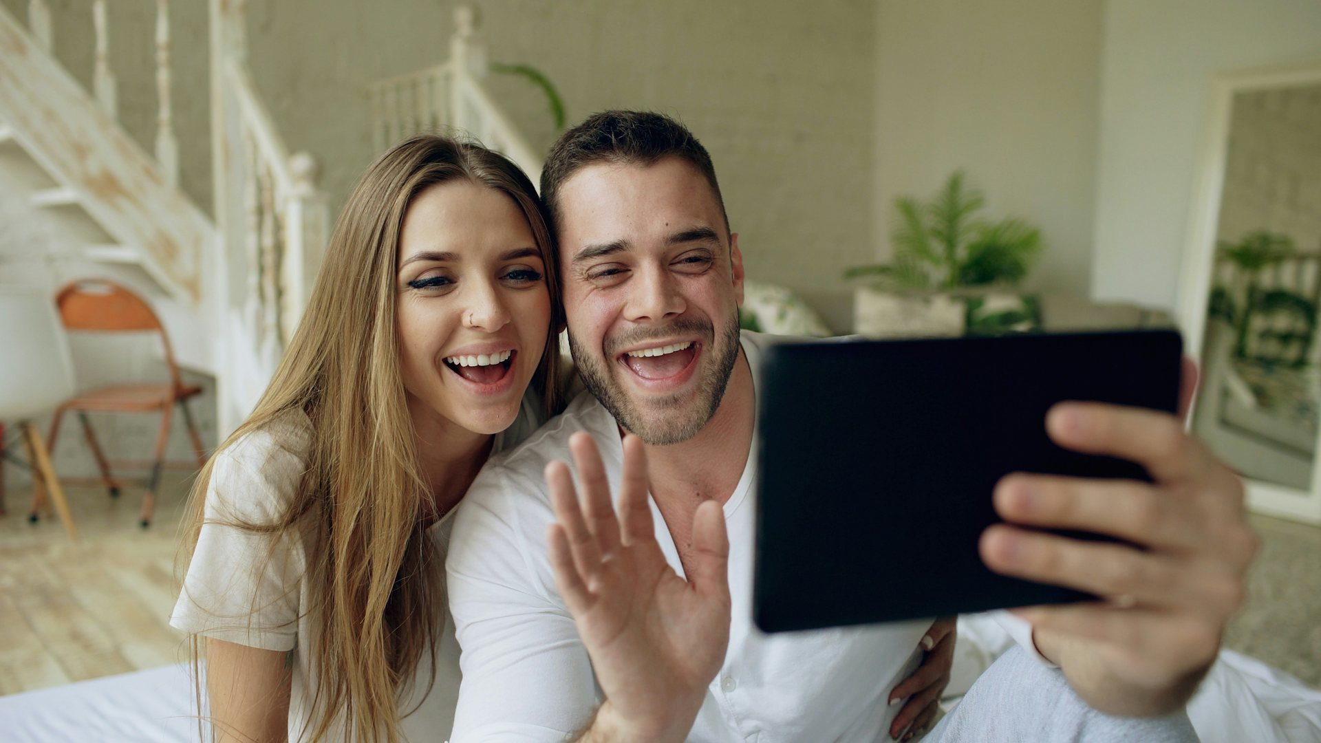 Woman laughing as she reads a message on her phone at home